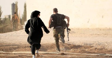A woman reporter runs with a fighter to avoid snipers at the front line in Syria's Aleppo, Oct. 10, 2014. (Reuters Photo)