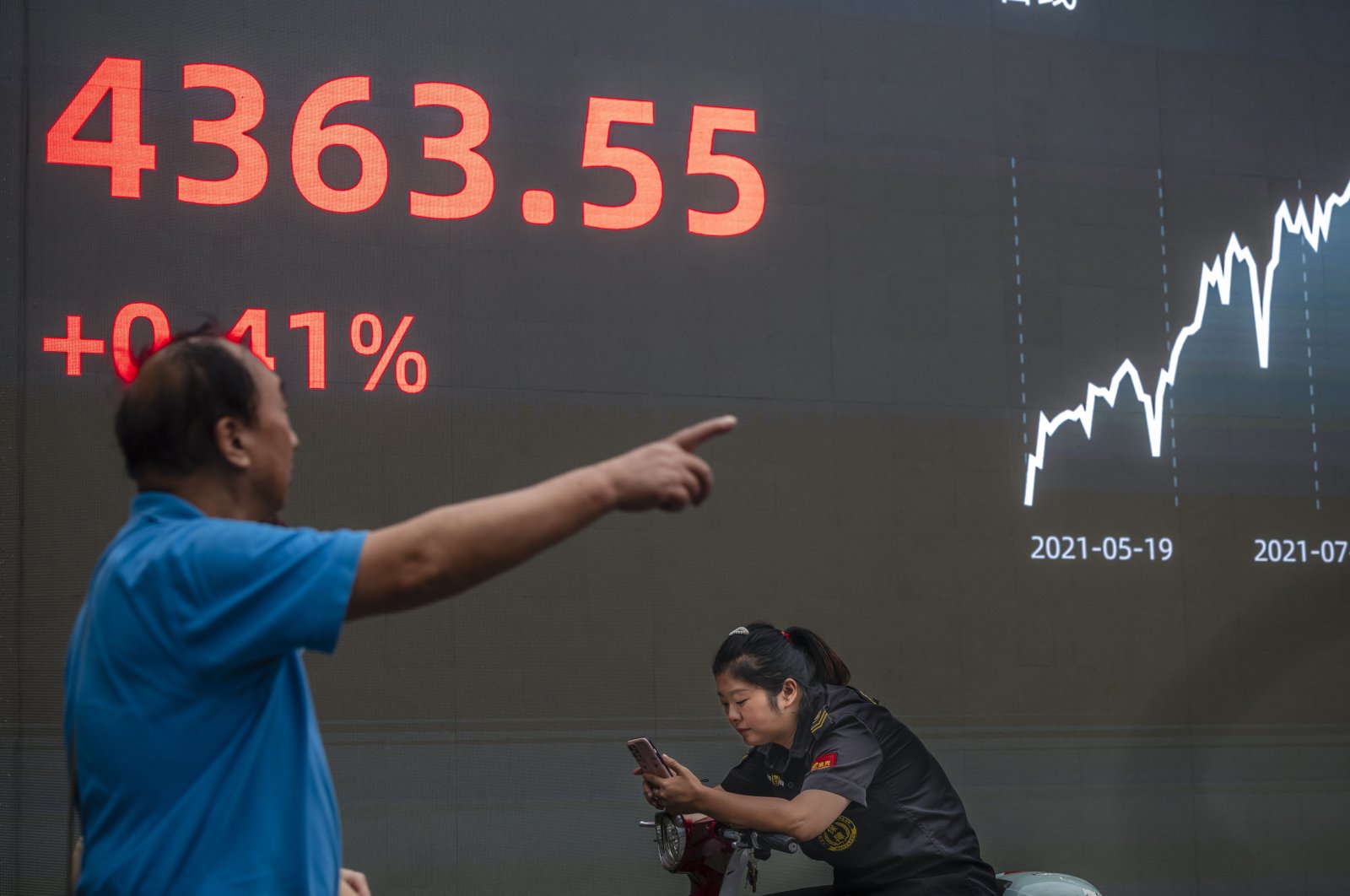 A man walks in front of the screen showing the newest stock exchange and economic data in Shanghai, China, Oct. 7, 2021. (EPA Photo)