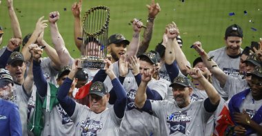 Atlanta Braves manager Brian Snitker hoists the trophy as players and staff celebrate the baseball World Series win over the Houston Astros, Houston, Texas, U.S., Nov. 2, 2021. (AP Photo)
