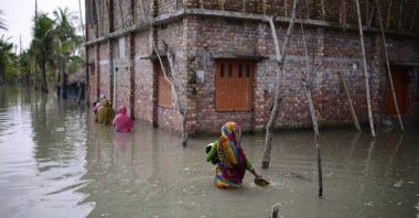 Villagers wade through waist-deep waters to reach their homes in Pratap Nagar that lies in the Shyamnagar region, in Satkhira, Bangladesh on Oct. 5, 2021. (AP Photo)