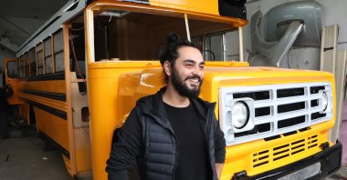 Kadir Mert, 30, stands in front of his refurbished U.S.-style school bus, Samsun, northwestern Turkey, Nov. 11, 2021. (IHA Photo)