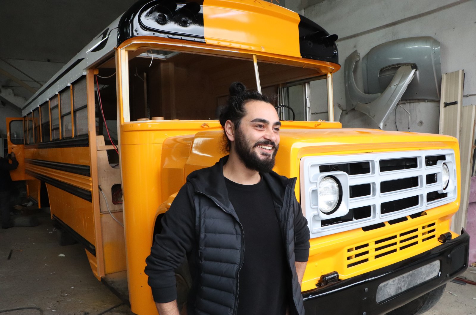 Kadir Mert, 30, stands in front of his refurbished U.S.-style school bus, Samsun, northwestern Turkey, Nov. 11, 2021. (IHA Photo)