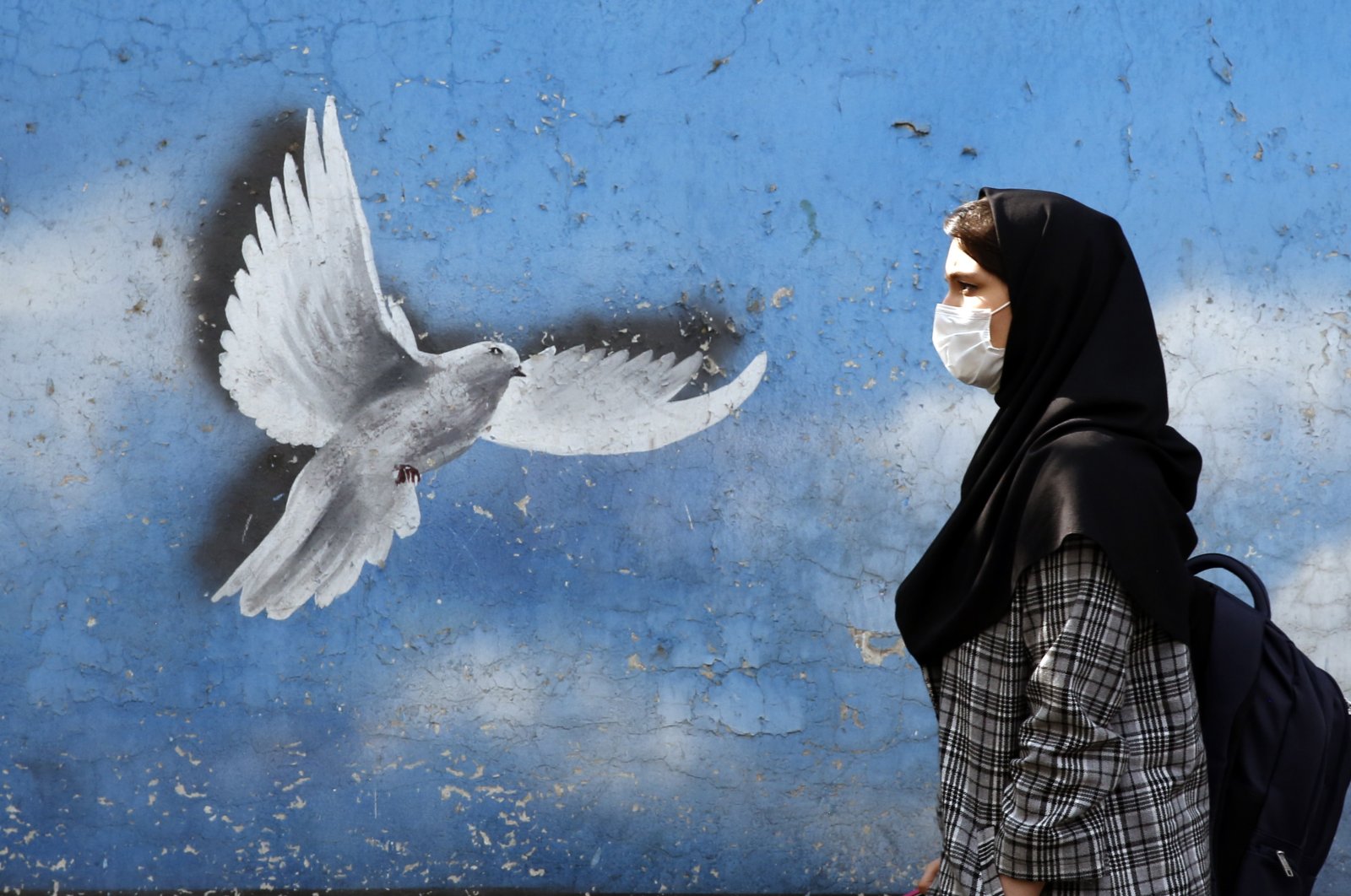 An Iranian woman walks past a mural depicting a flying dove at a street in Tehran, Iran, Nov. 01, 2021. (EPA Photo)