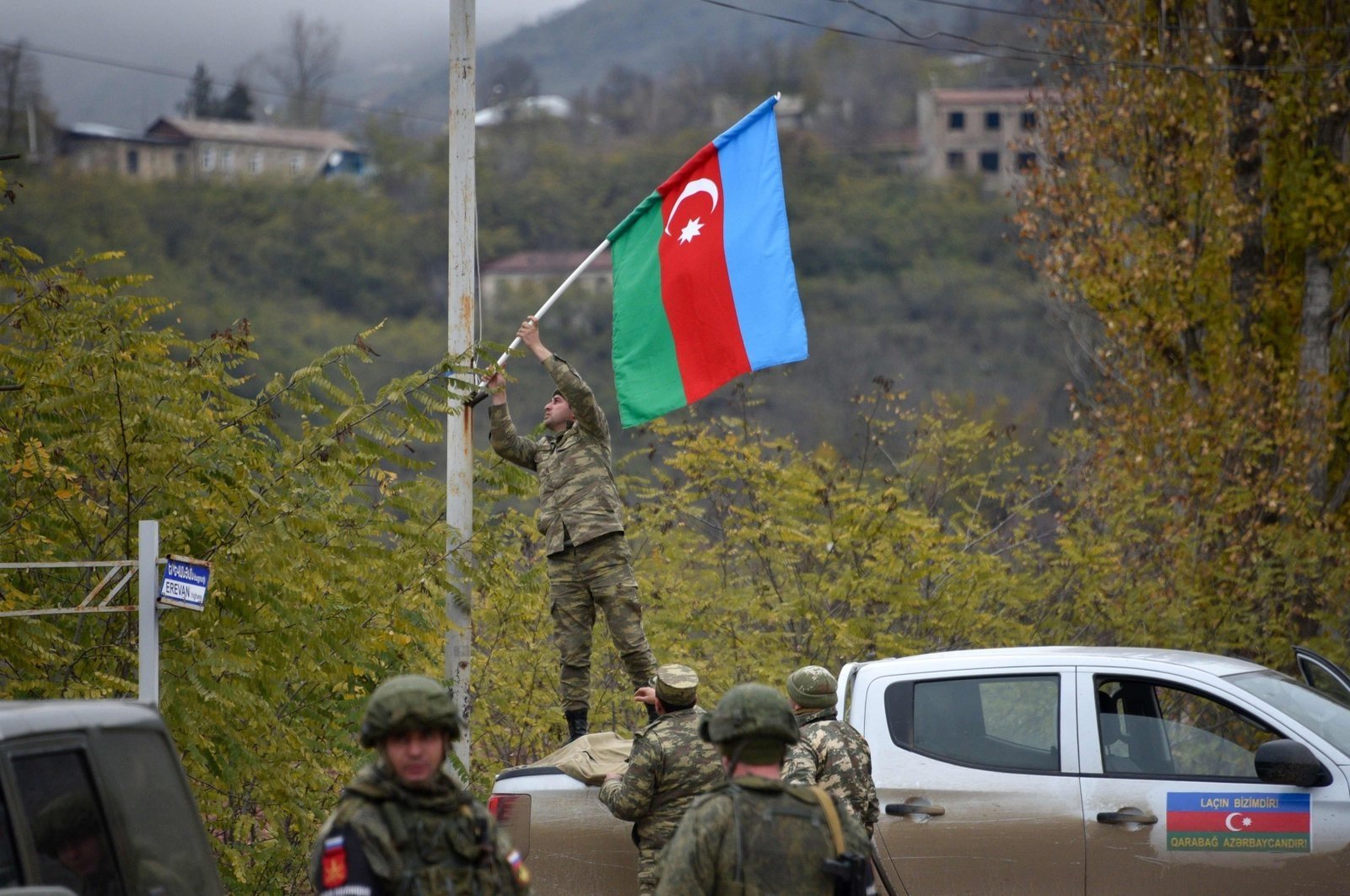 An Azerbaijani soldier fixes a national flag on a lamppost in the town of Lachin, the Nagorno-Karabakh region, Azerbaijan, Dec. 1, 2020. (AFP Photo)