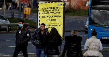 People walk past a sign encouraging the public to get their coronavirus (COVID-19) vaccine doses in Manchester, Britain, Oct. 25, 2021. (Reuters Photo)