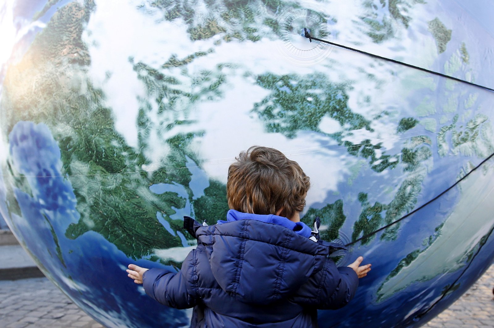 A child embraces a globe shaped balloon during a rally held ahead of the start of the 2015 Paris World Climate Change Conference, known as the COP21 summit, in Rome, Italy , Nov. 29, 2015. (Reuters Photo)