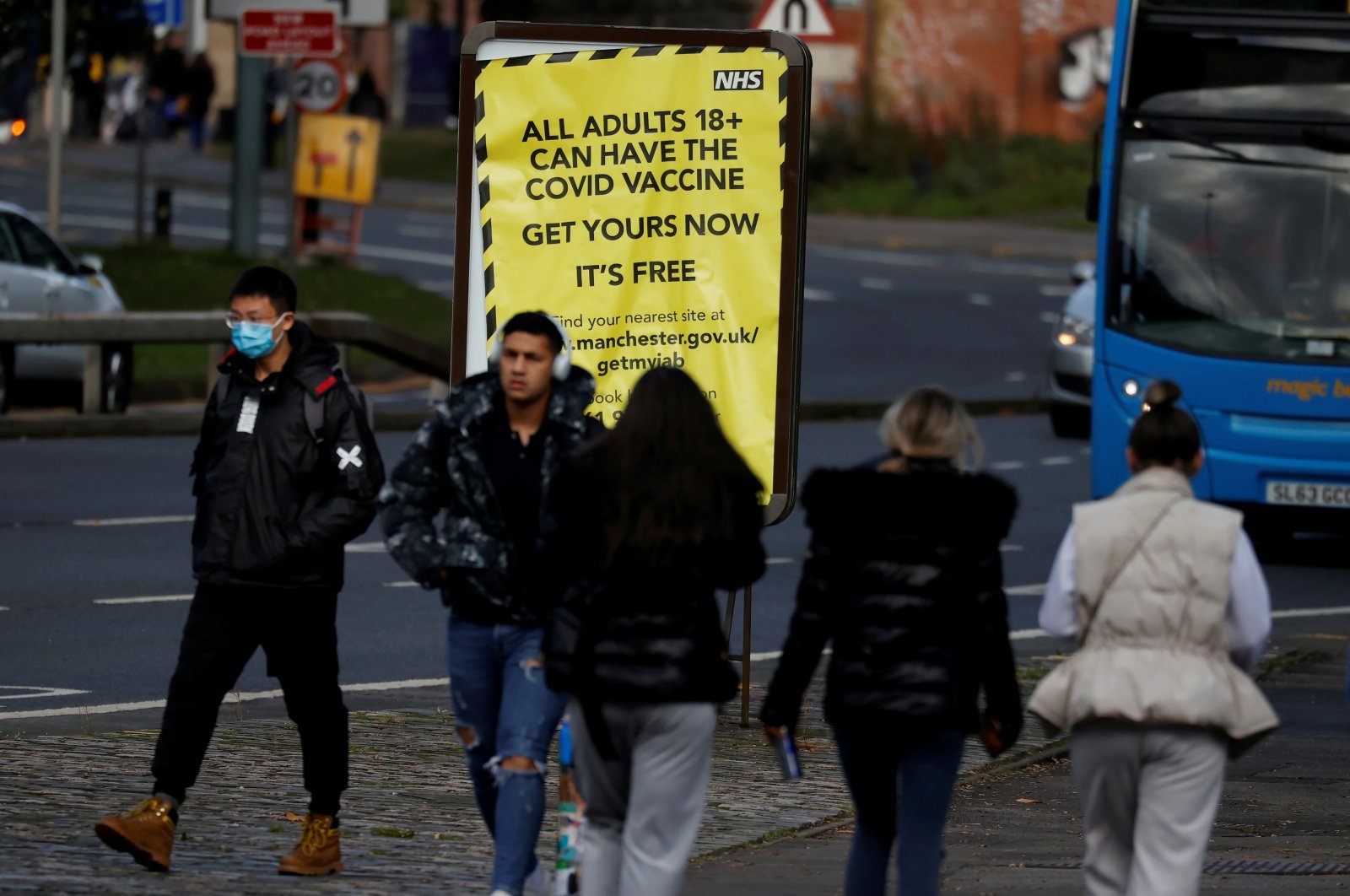 People walk past a sign encouraging the public to get their coronavirus (COVID-19) vaccine doses in Manchester, Britain, Oct. 25, 2021. (Reuters Photo)