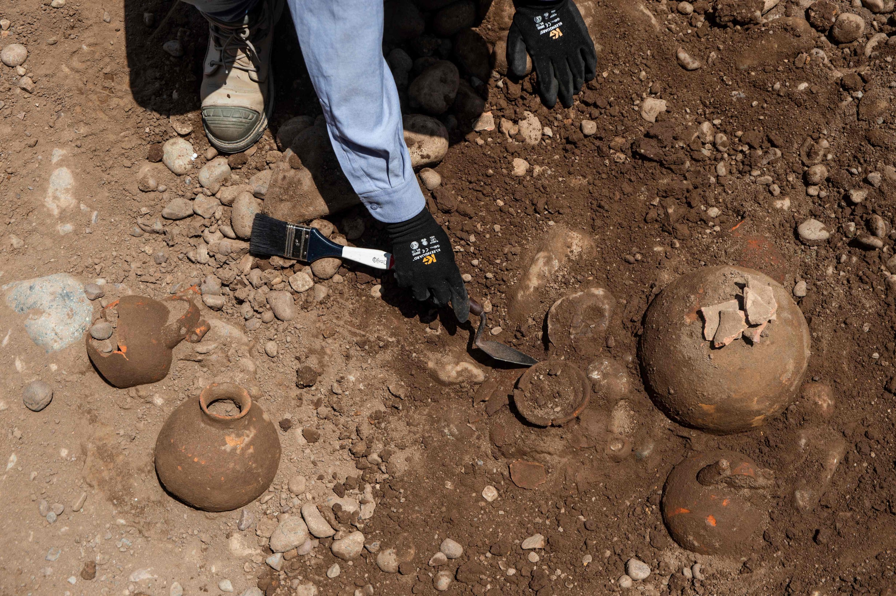 Specialists work around ancient vessels found by a crew laying a natural gas pipe under a street in Lima, Peru, Nov. 4, 2021. (AFP Photo)
