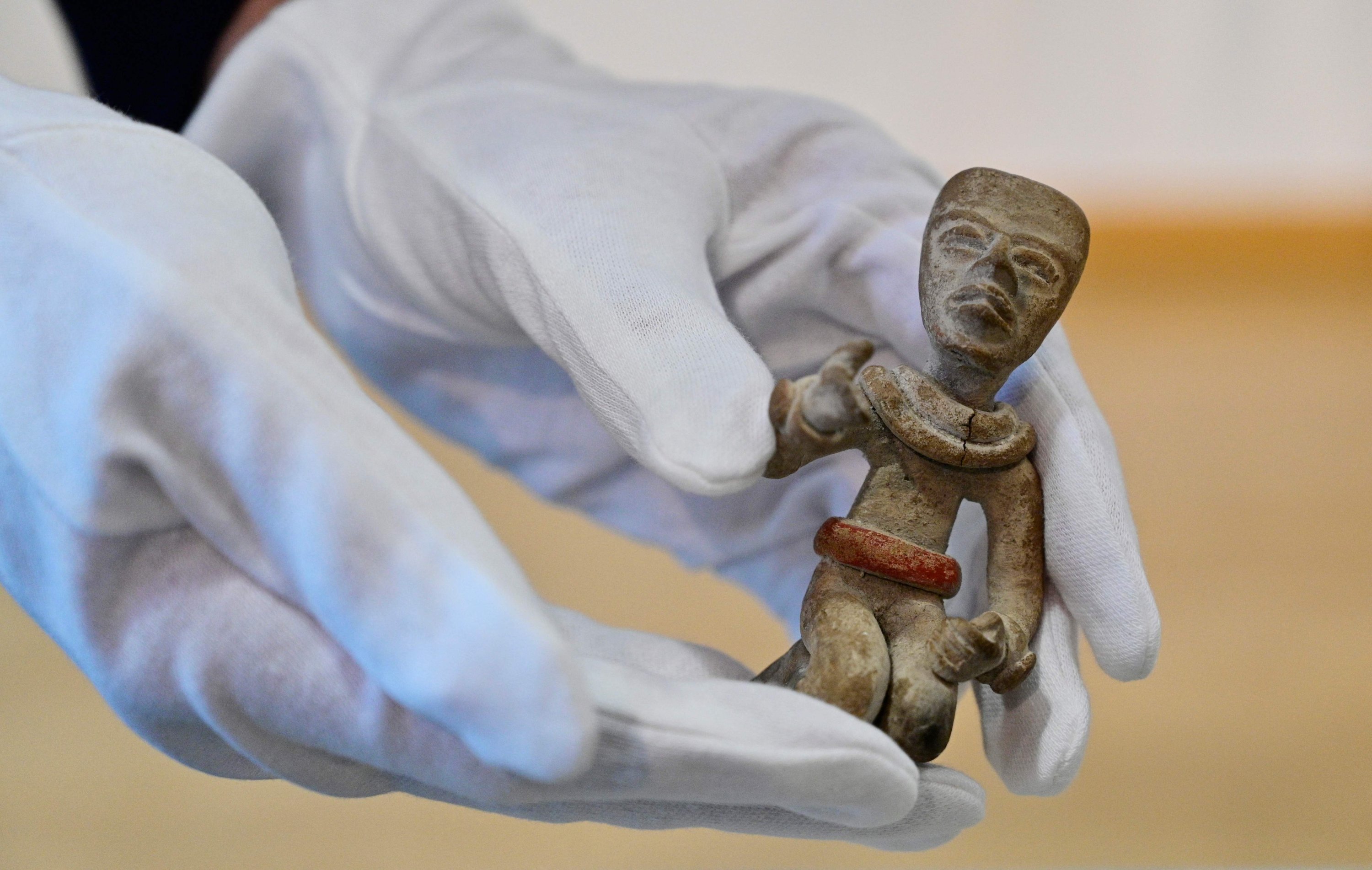 A person holds a 'Kneeling Figure' during a handing over ceremony of a small trove of Mayan cultural artifacts being returned to Mexico and Guatemala in Berlin, Germany, Nov. 5, 2021. (AFP Photo)