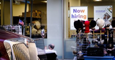 A street vendor (L) sits near a sign advertising job openings in a retail store in New York, U.S., Oct. 20, 2021. (EPA Photo)