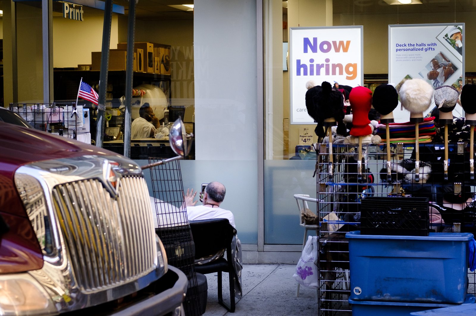 A street vendor (L) sits near a sign advertising job openings in a retail store in New York, U.S., Oct. 20, 2021. (EPA Photo)