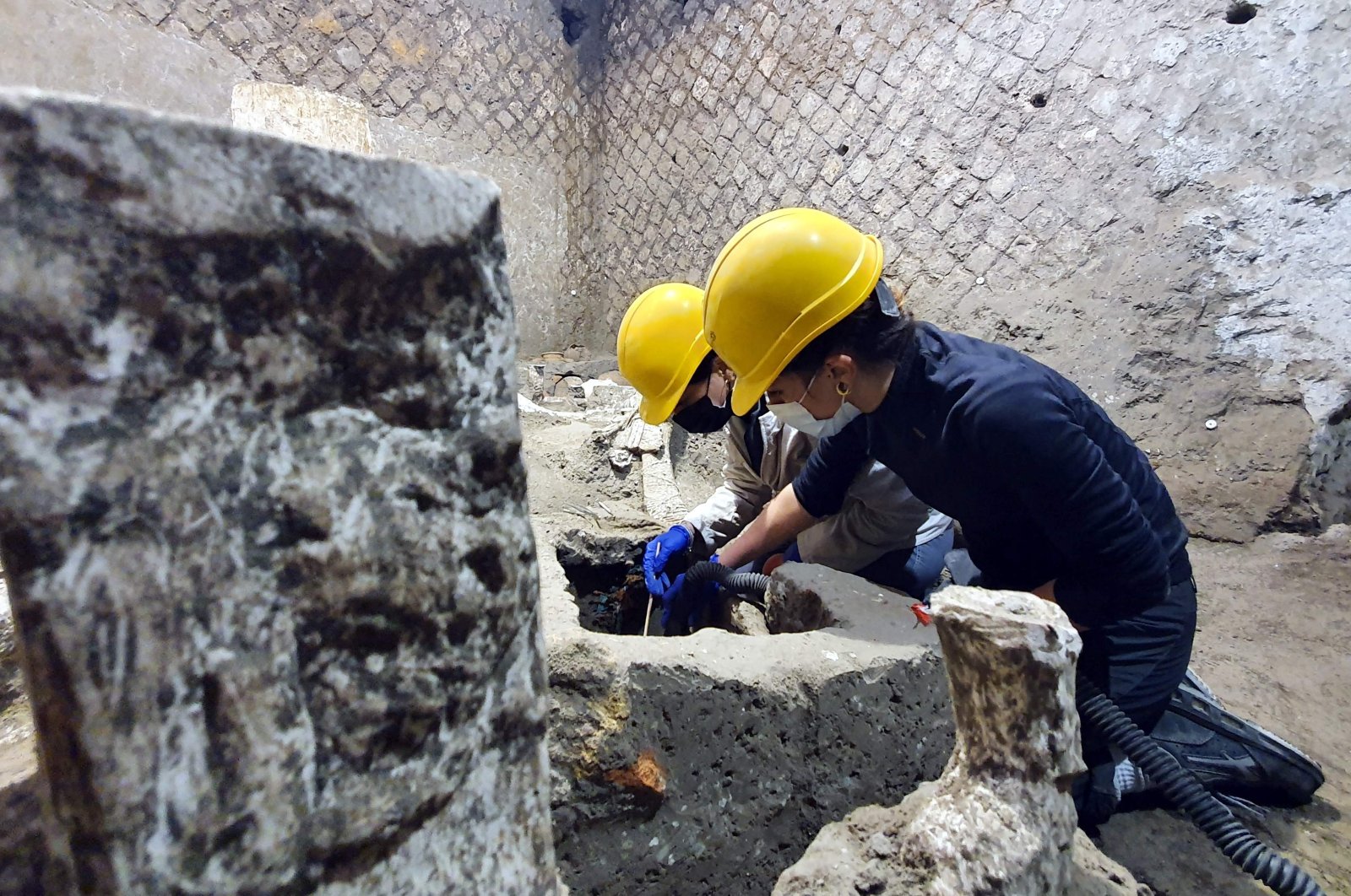 A photo handout on Nov. 6, 2021, by the Pompeii Archaeological Park shows archaeologists working in "The room of Slaves," an exceptionally well-preserved room for the slaves who worked in Villa Civita Giuliana in Pompeii, a villa where a ceremonial chariot and a stable with a harnessed horses were earlier unearthed. (POMPEI ARCHAEOLOGICAL PARK via AFP Photo)