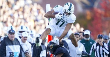 Michigan State running back Connor Heyward (11) leaps over Purdue safety Marvin Grant (4) during the first half of an NCAA college football game, West Lafayette, Indiana, U.S., Nov. 6, 2021. (AP Photo)