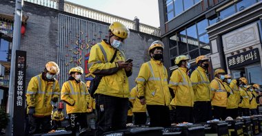 Food delivery drivers for online shopping platform Meituan stand in formation before starting work along a street in Beijing, China, Oct. 19, 2021. (AFP Photo)