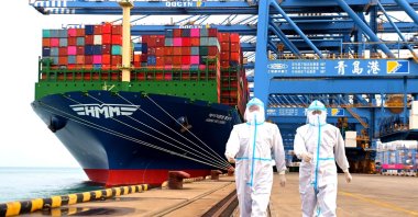 China immigration inspection officers in protective overalls near a container ship at a port in Qingdao in eastern Shandong province, China, Nov. 7, 2021. (AP Photo)