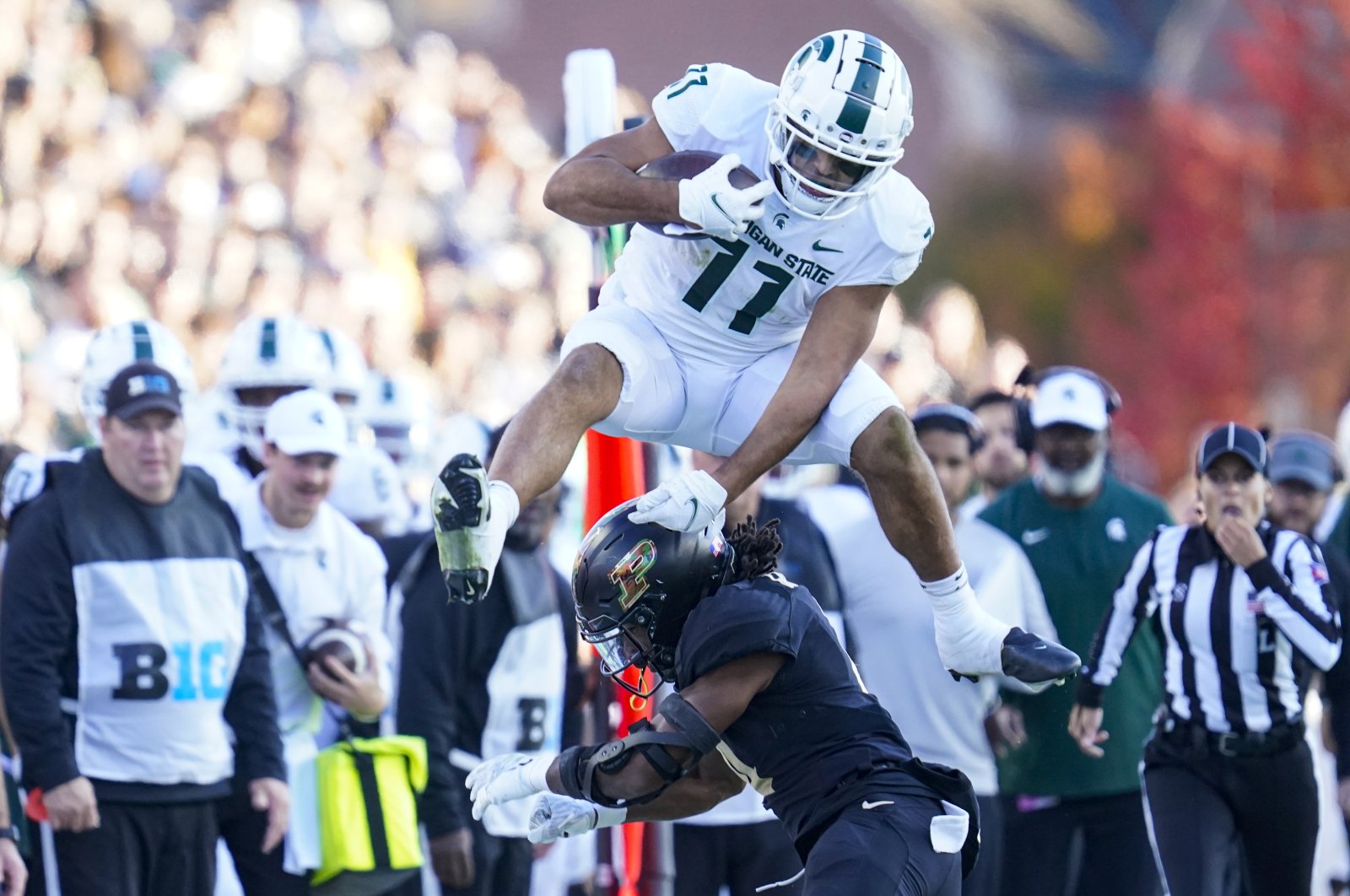 Michigan State running back Connor Heyward (11) leaps over Purdue safety Marvin Grant (4) during the first half of an NCAA college football game, West Lafayette, Indiana, U.S., Nov. 6, 2021. (AP Photo)