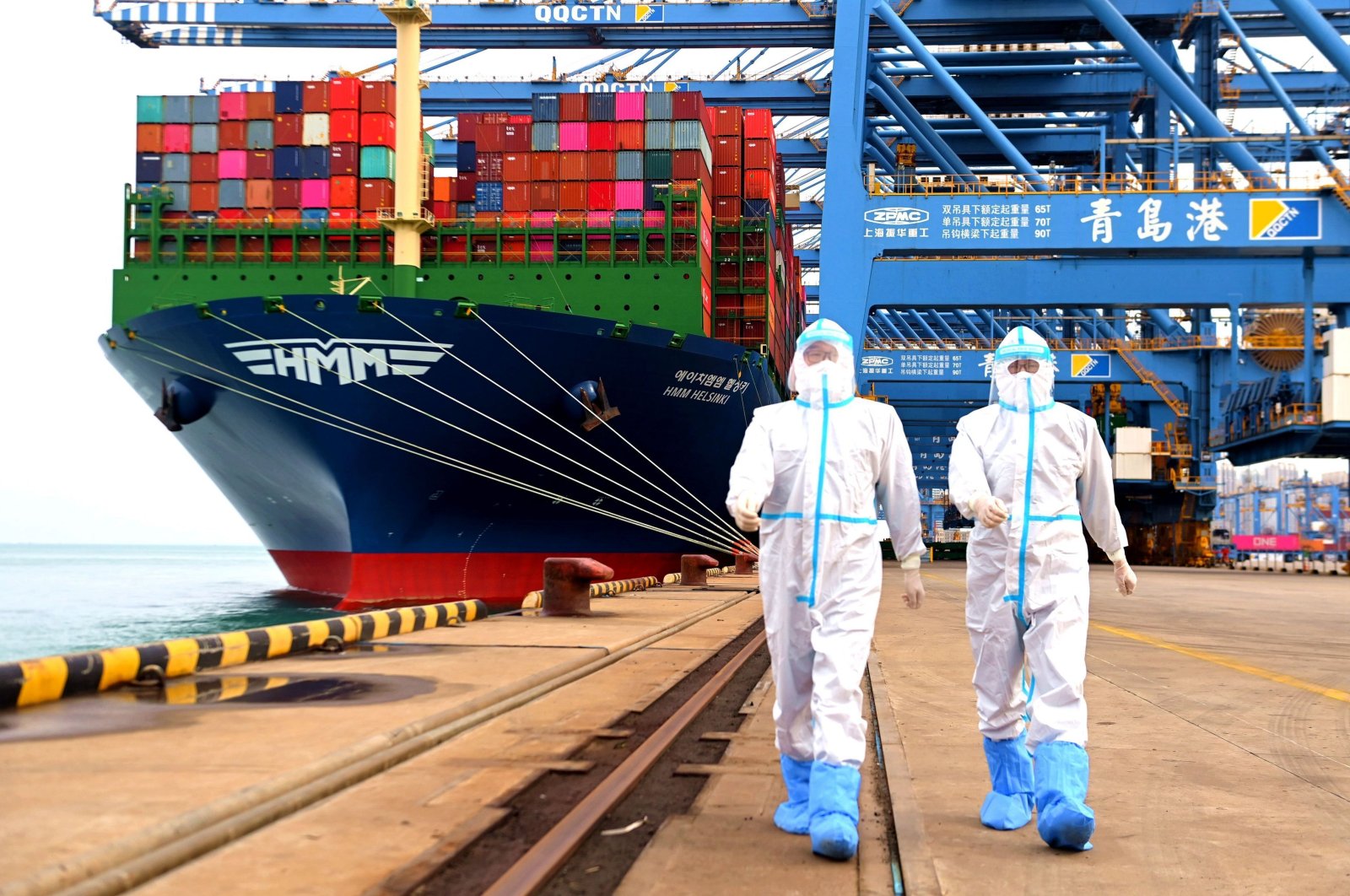 China immigration inspection officers in protective overalls near a container ship at a port in Qingdao in eastern Shandong province, China, Nov. 7, 2021. (AP Photo)