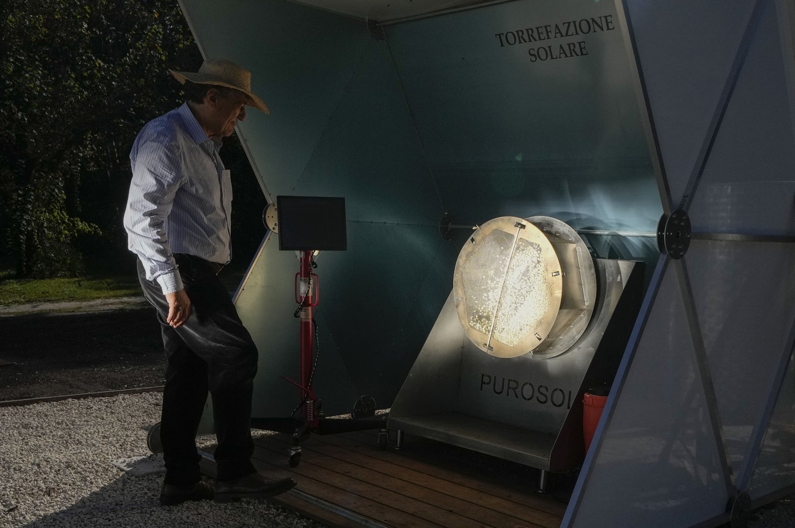 Antonio Durbe monitors the functioning of the "Purosole," or Pure Sun, solar light coffee roaster, in Rome, Italy, Oct. 13, 2021. (AP Photo)