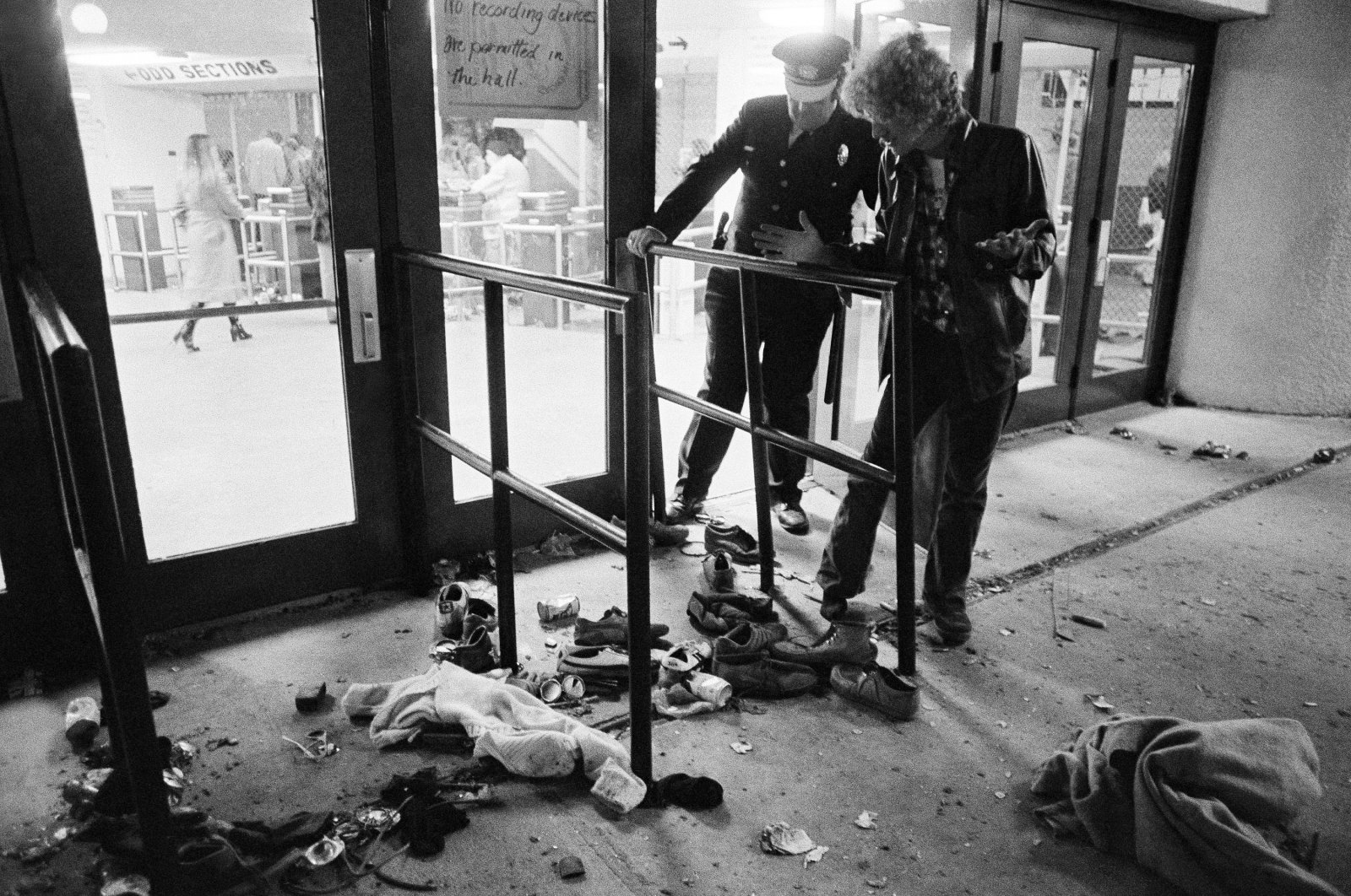 A security guard and an unidentified man look at an area where several people were killed and others injured, as they were caught in a surging crowd entering the Riverfront Coliseum for a The Who concert, in Cincinnati, United States, Dec. 3, 1979. (AP Photo)