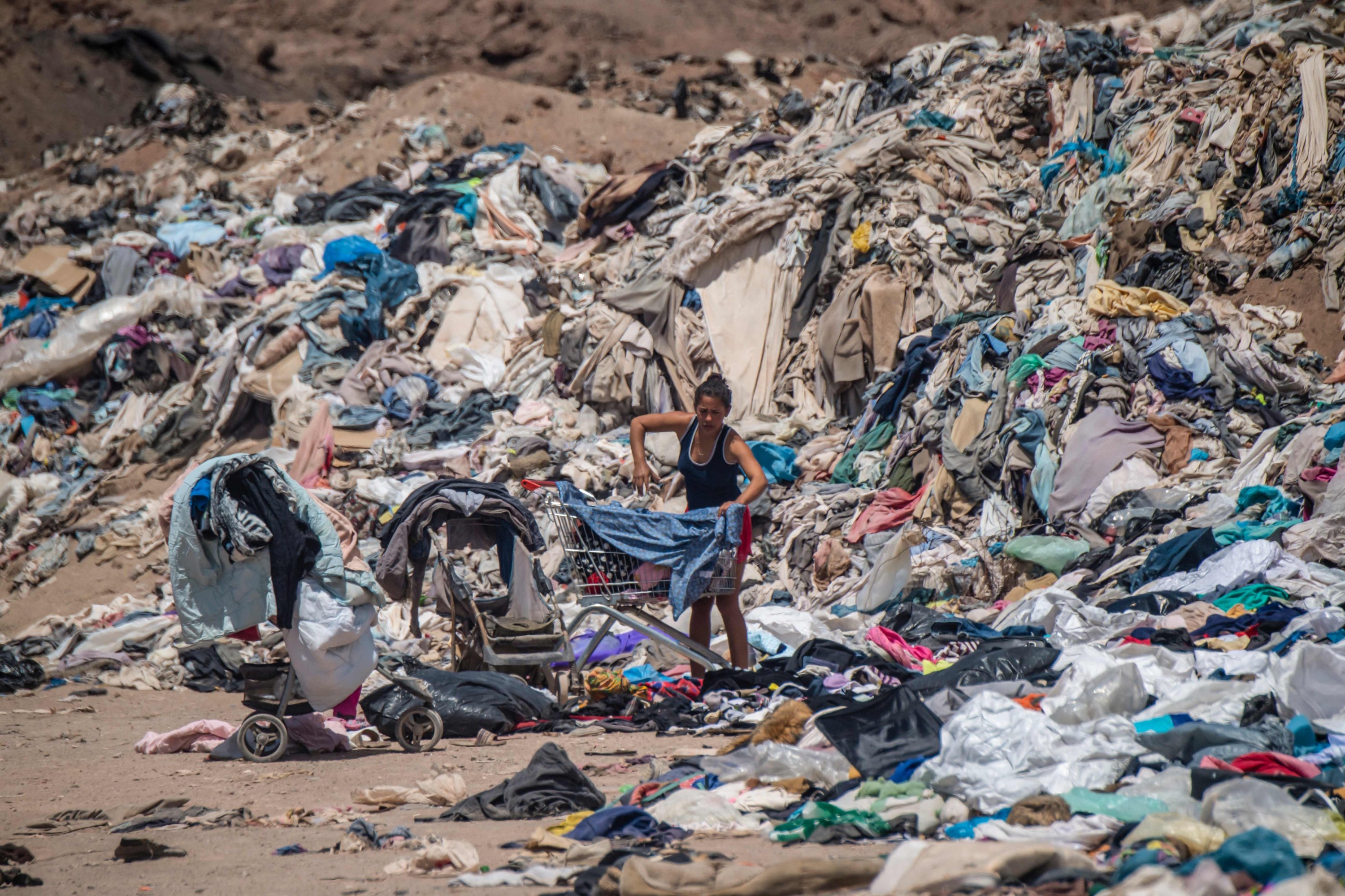 Wanita mencari pakaian bekas di antara banyak barang yang dibuang di gurun Atacama, di Alto Hospicio, Iquique, Chili, 26 September 2021. (AFP Photo)