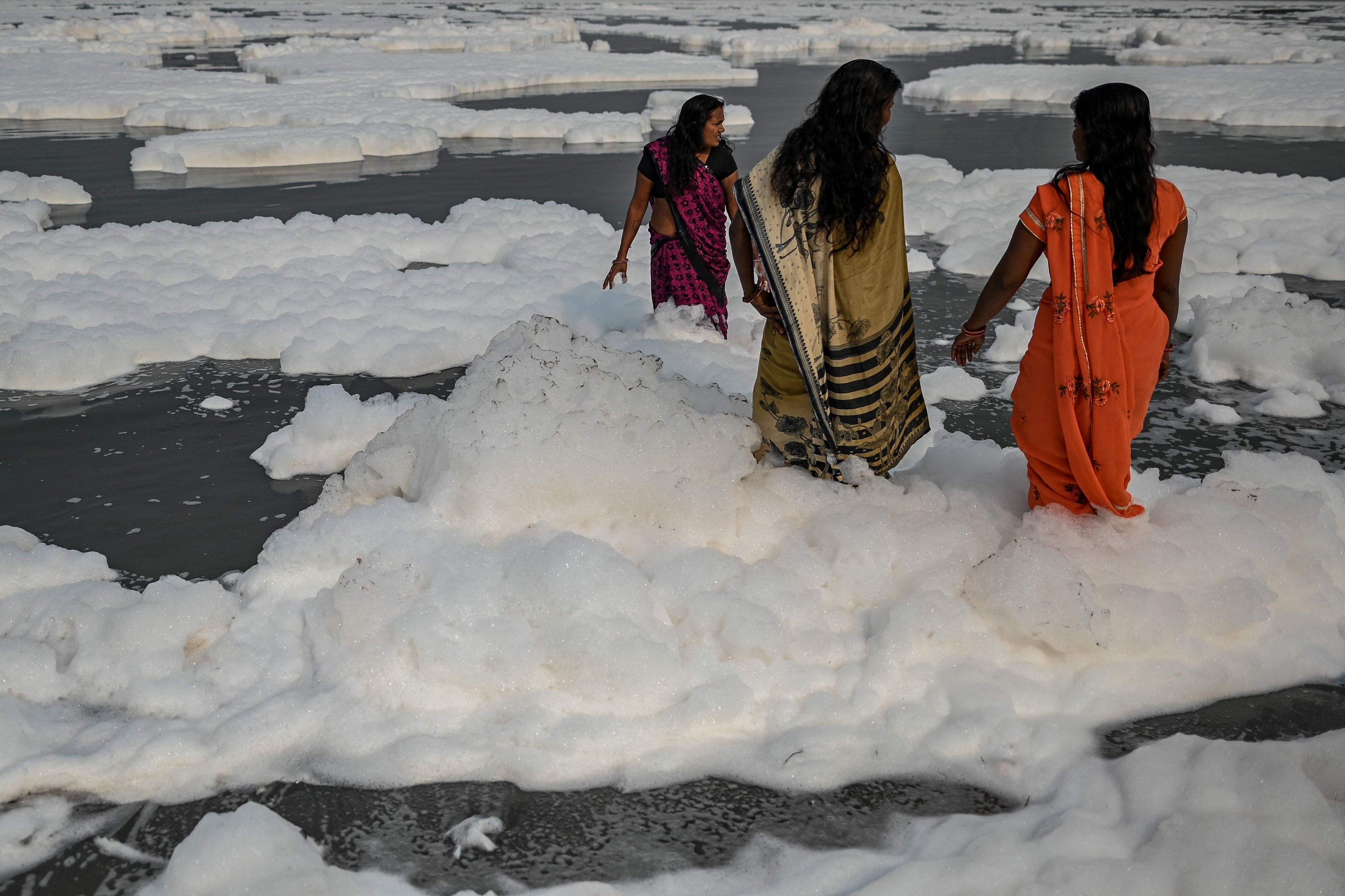 Women devotees take a dip in the waters of Yamuna river as a part of rituals for the upcoming Hindu festival of Chhat Puja amid foam created by pollution in the water in New Delhi on Nov. 8, 2021. (AFP Photo)