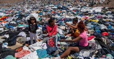 Women search for used clothes amid tons of discarded items in the Atacama desert, in Alto Hospicio, Iquique, Chile, Sept. 26, 2021. (AFP Photo)