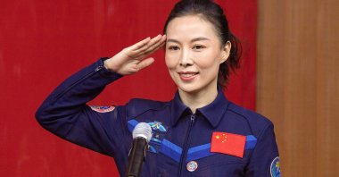 Chinese astronaut Wang Yaping, member of the second crew for China's new space station, salutes during a briefing the day before the launch at the Jiuquan Satellite Launch Center in the Gobi Desert, in northwest China, Oct. 14, 2021. (AFP Photo)