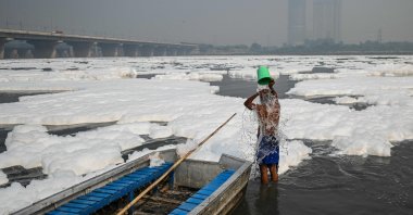 A man bathes in the waters of Yamuna river amid foam created by pollution in the water in New Delhi on Nov. 8, 2021. (AFP Photo)