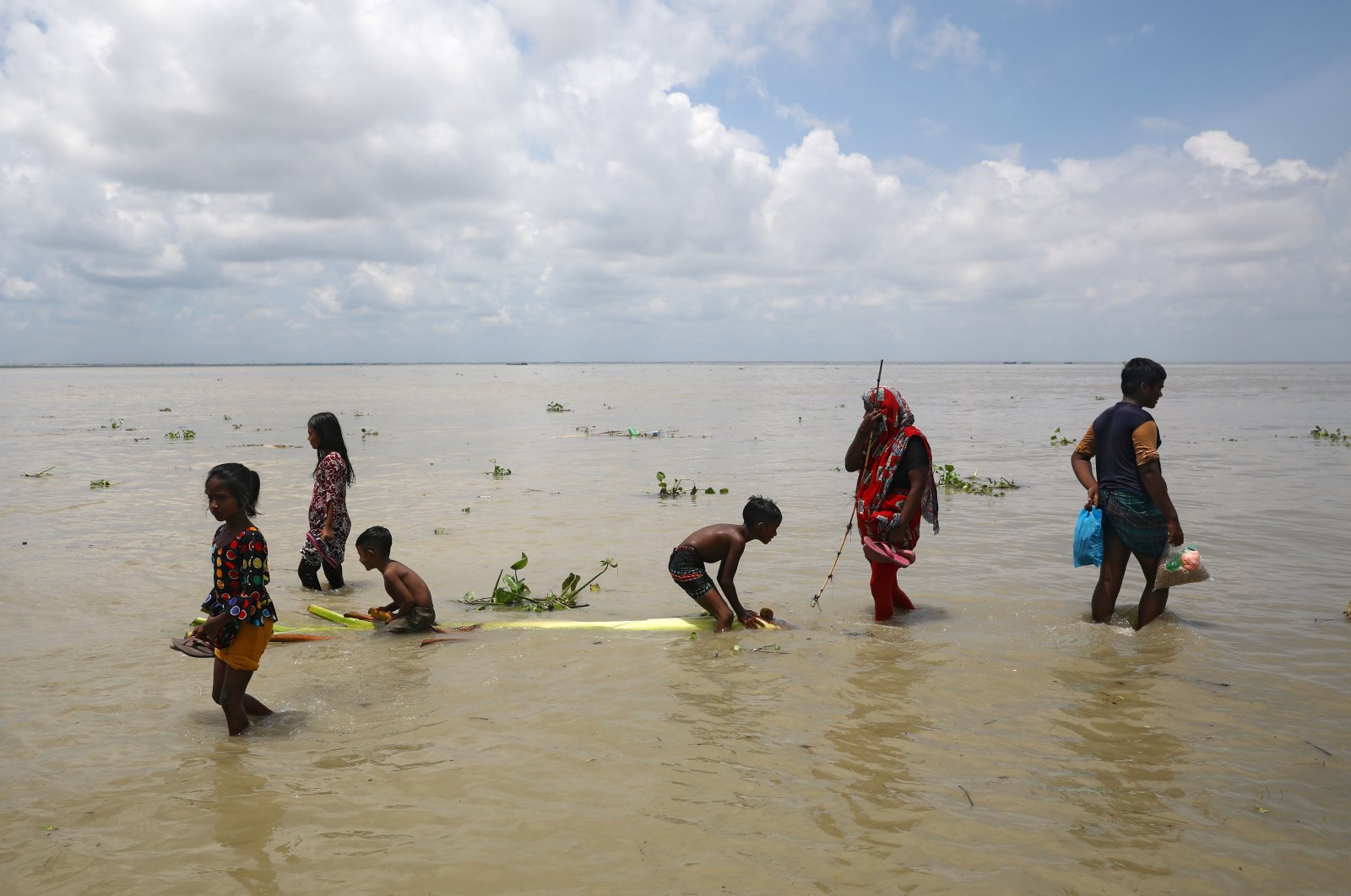People walk in a street flooded by the Padma River as the flood situation worsens in Munshiganj district, on the outskirts of Dhaka, Bangladesh, July 25, 2020. (Reuters Photo)