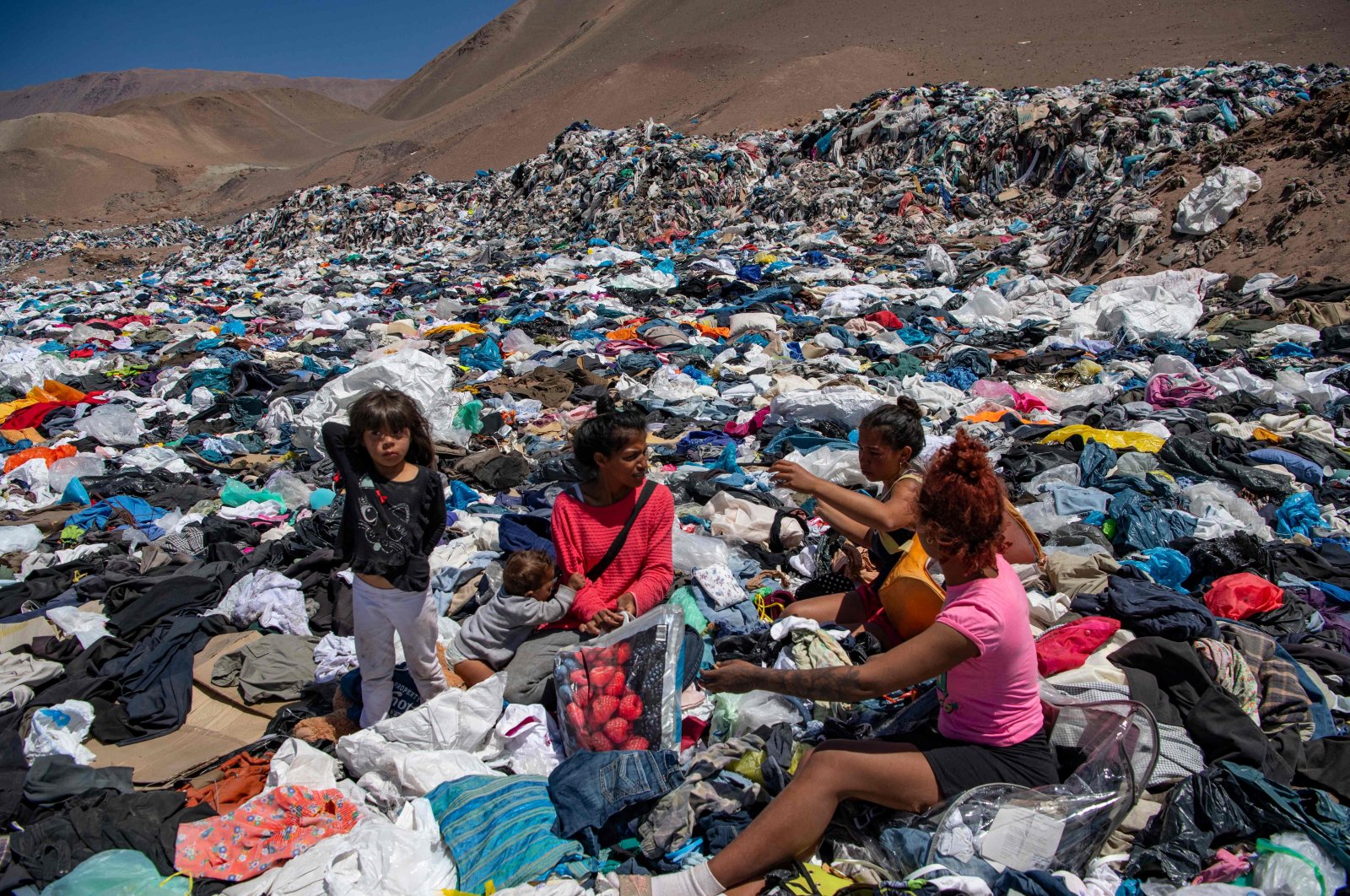Women search for used clothes amid tons of discarded items in the Atacama desert, in Alto Hospicio, Iquique, Chile, Sept. 26, 2021. (AFP Photo)