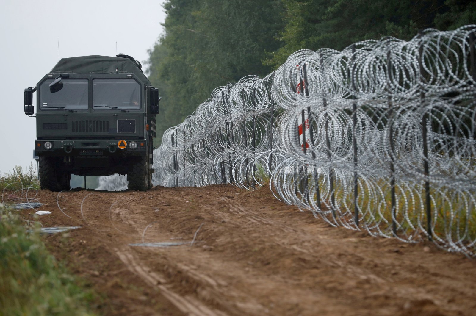 A view of a vehicle next to a fence built by Polish soldiers on the border between Poland and Belarus near the village of Nomiki, Poland, Aug. 26, 2021. (Reuters Photo)