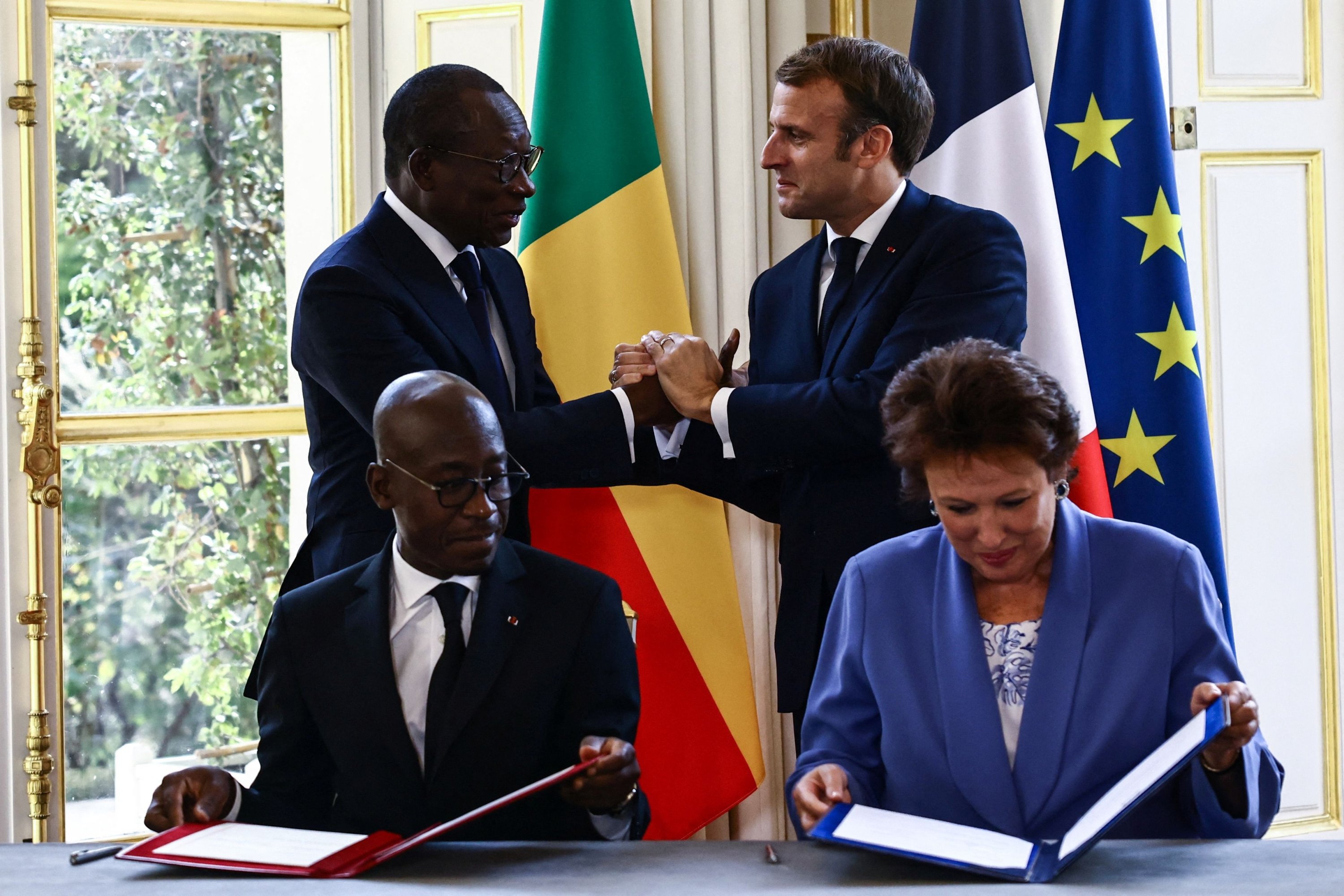 Presiden Emmanuel Macron menyapa Presiden Patrice Talon saat Menteri Roselyne Bachelot dan Menteri Jean-Michel Abimbola menandatangani kesepakatan tentang pengembalian artefak budaya yang dijarah, di Istana Elysee di Paris, Prancis, 9 November 2021. (AFP Photo)