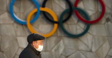 A man walks past the Olympic rings on the exterior of the National Stadium, which will be a venue for the upcoming 2022 Winter Olympics, in Beijing, China, Feb. 2, 2021. (AP Photo)