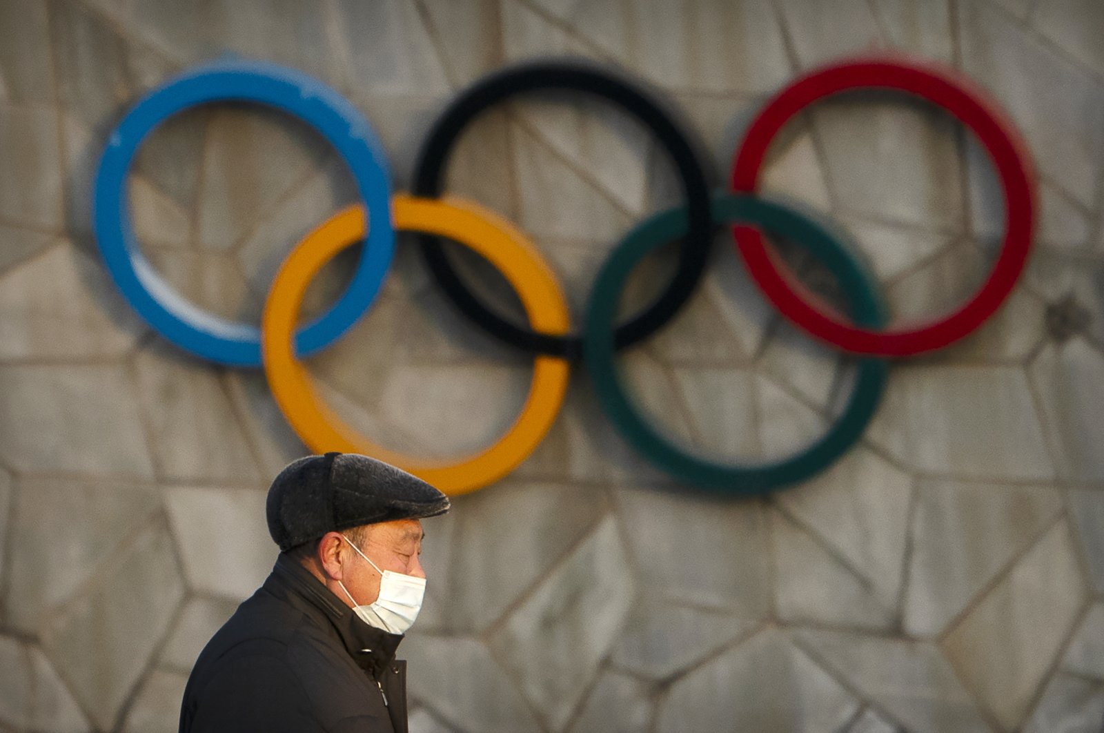 A man walks past the Olympic rings on the exterior of the National Stadium, which will be a venue for the upcoming 2022 Winter Olympics, in Beijing, China, Feb. 2, 2021. (AP Photo)