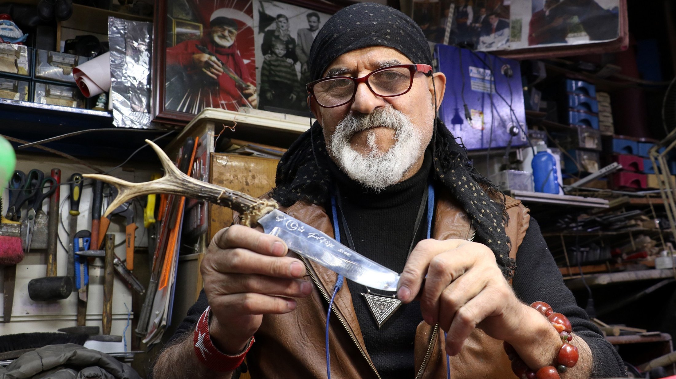 Erdoğan Güzel, pembuat pisau terkecil di dunia, menunjukkan salah satu pisaunya di bengkelnya, di Sivas, Turki, 10 November 2021. (Foto IHA)