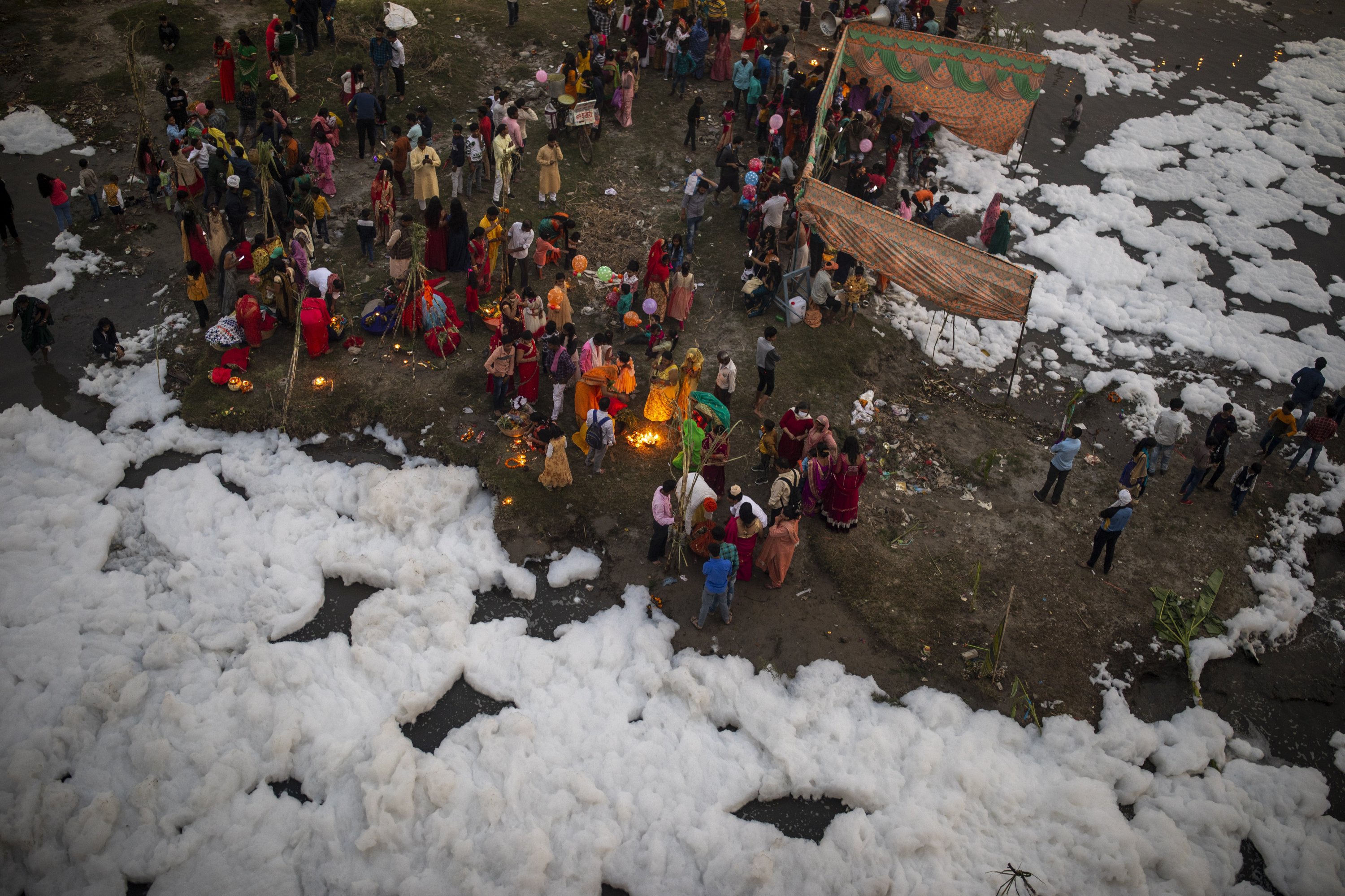 Indian Hindu devotees perform rituals on the banks of Yamuna river, covered by chemical foam caused due to industrial and domestic pollution, during Chhath Puja festival in New Delhi, India, Nov. 10, 2021. (AP Photo)