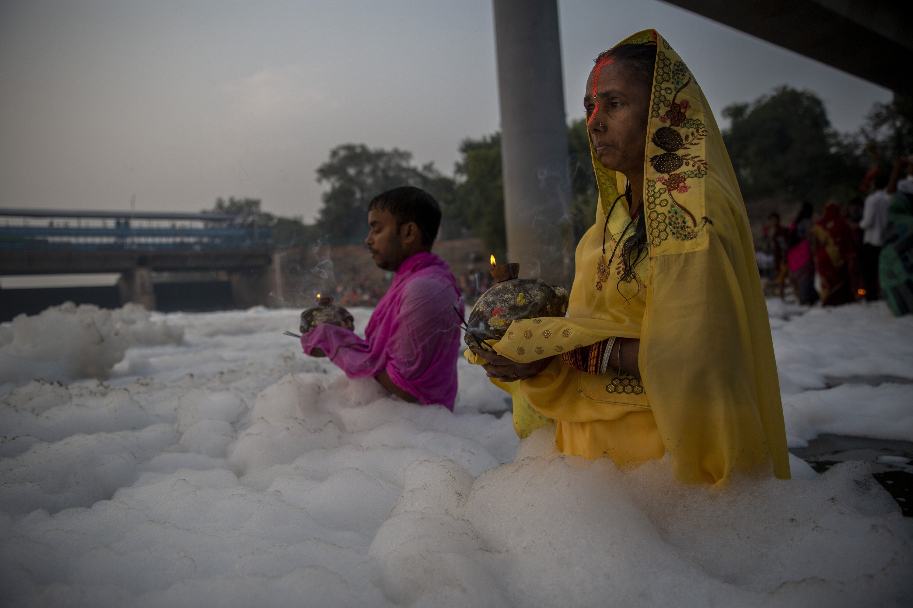 Umat ​​Hindu India melakukan ritual di sungai Yamuna, ditutupi oleh busa kimia yang disebabkan oleh polusi industri dan domestik, selama festival Chhath Puja di New Delhi, India, 10 November 2021. (AP Photo)