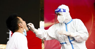 In this photo released by Xinhua News Agency, a medical worker collects a swab sample for a nucleic acid test in Ruili City of southwest China's Yunnan Province, on July 5, 2021. (AP Photo)
