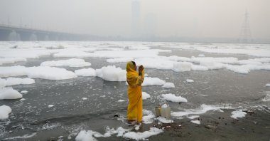 A woman prays on the banks of the river Yamuna on a smoggy morning in New Delhi, India, Nov. 8, 2021. (REUTERS Photo)