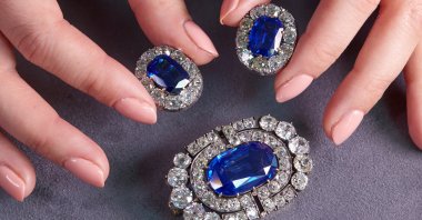 A staff member holds a historically valuable sapphire and diamond brooch and a pair of ear clips during a preview at Sotheby's, before their auction sale in Geneva, Switzerland, Nov. 2, 2021.  (Reuters Photo)
