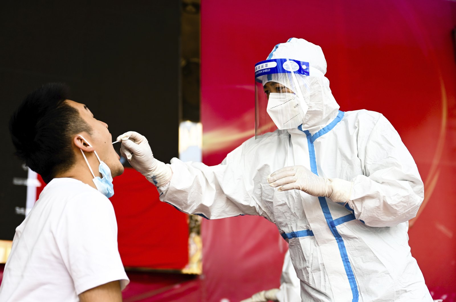 In this photo released by Xinhua News Agency, a medical worker collects a swab sample for a nucleic acid test in Ruili City of southwest China's Yunnan Province, on July 5, 2021. (AP Photo)