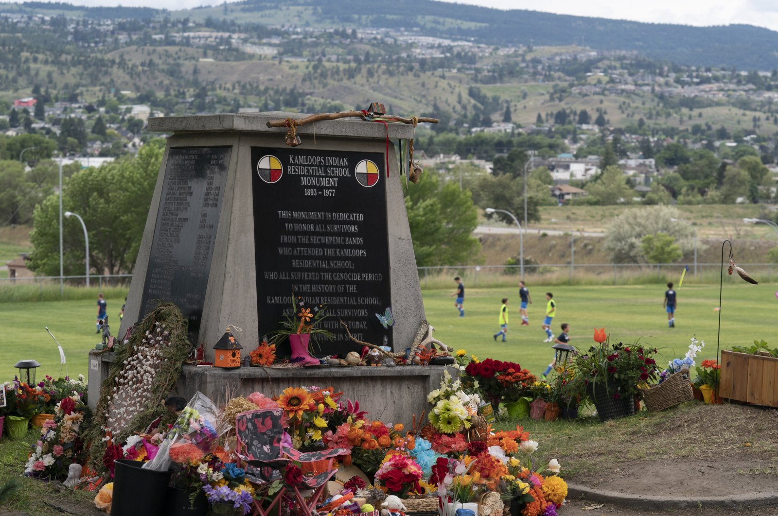 Children play soccer in the background as a memorial is pictured outside the Residential School in Kamloops, British Columbia, June, 13, 2021. (AP Photo)