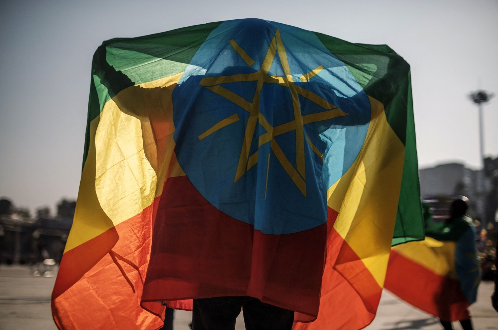 A man covers himself with an Ethiopian flag during a rally in support of the national defense forces, Addis Ababa, Ethiopia, Nov. 7, 2021. (AFP Photo)