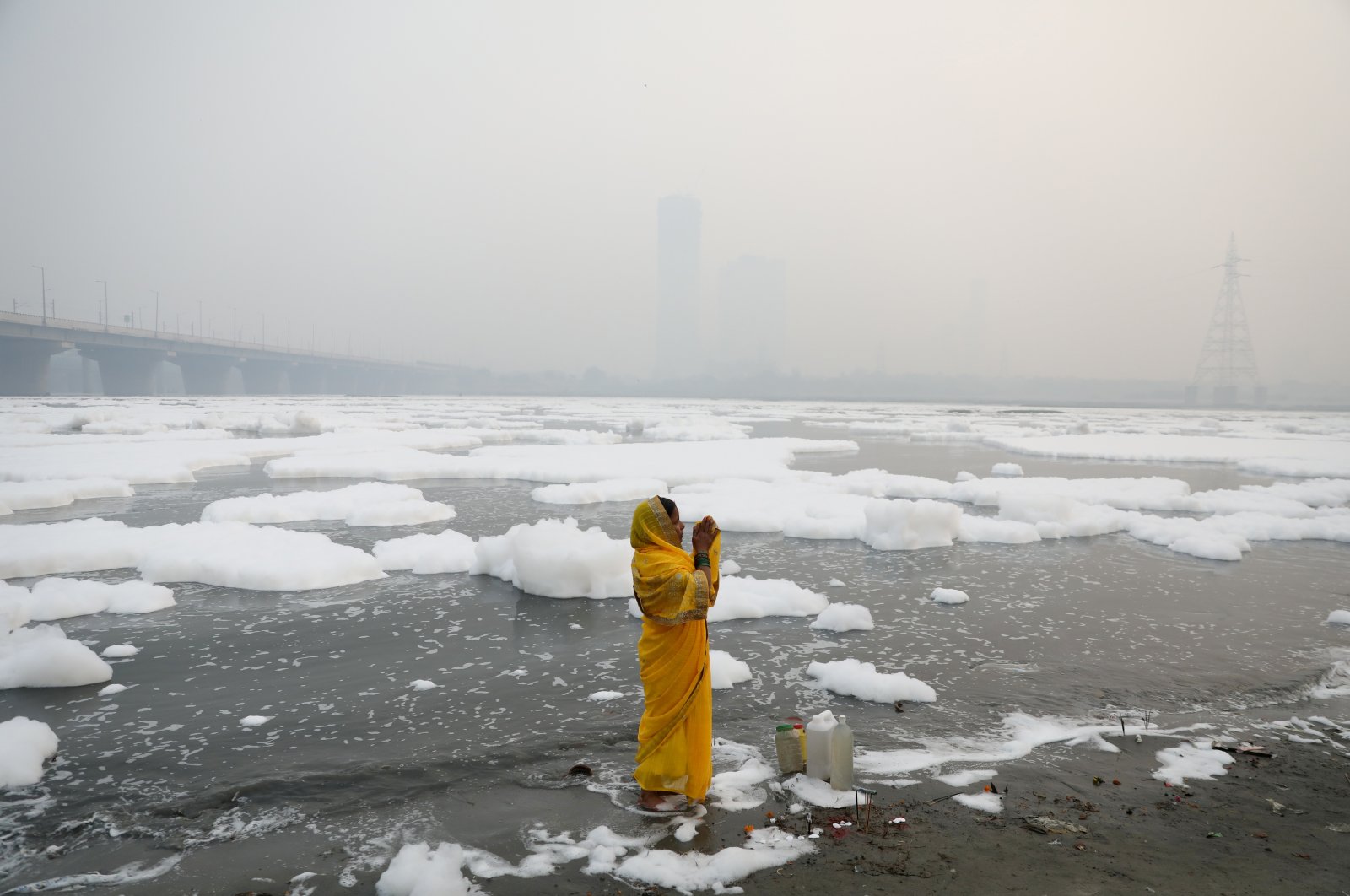 A woman prays on the banks of the river Yamuna on a smoggy morning in New Delhi, India, Nov. 8, 2021. (REUTERS Photo)