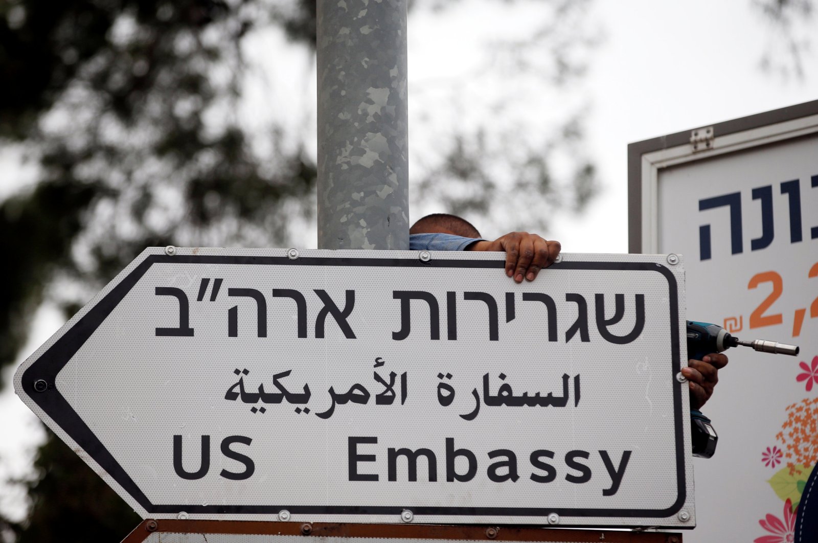A worker hangs a road sign directing to the U.S. Embassy, in the area of the U.S. Consulate in East Jerusalem, occupied Palestine, May 7, 2018. (Reuters File Photo)