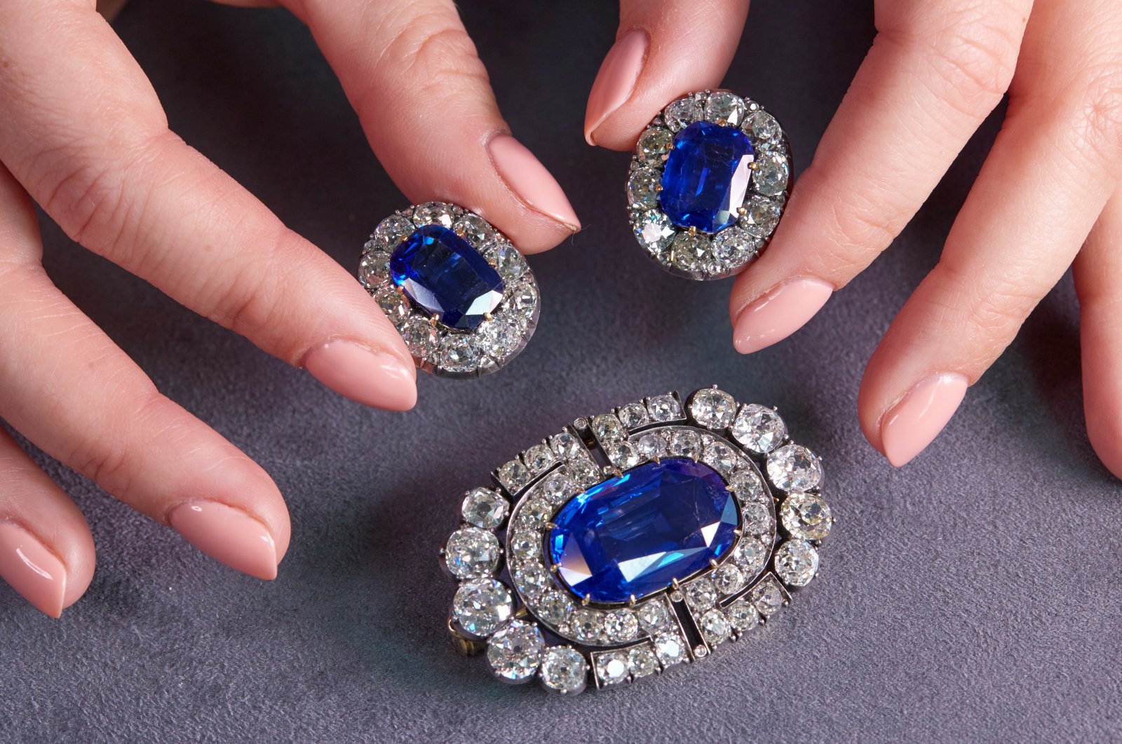 A staff member holds a historically valuable sapphire and diamond brooch and a pair of ear clips during a preview at Sotheby's, before their auction sale in Geneva, Switzerland, Nov. 2, 2021.  (Reuters Photo)