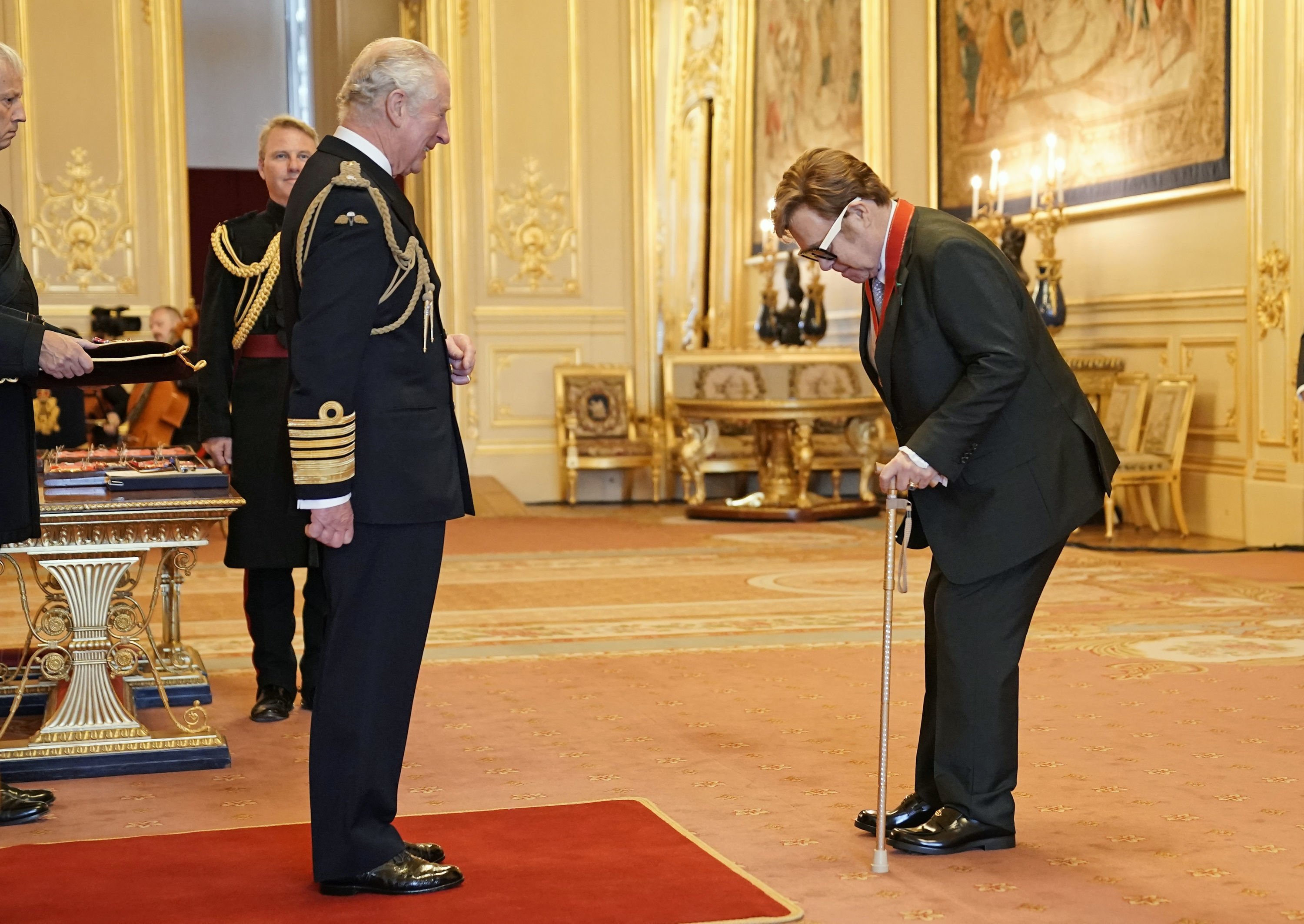 Sir Elton John memberi hormat kepada Pangeran Charles saat upacara penobatan di Kastil Windsor, di Windsor, Inggris, 10 November 2021. (AP)