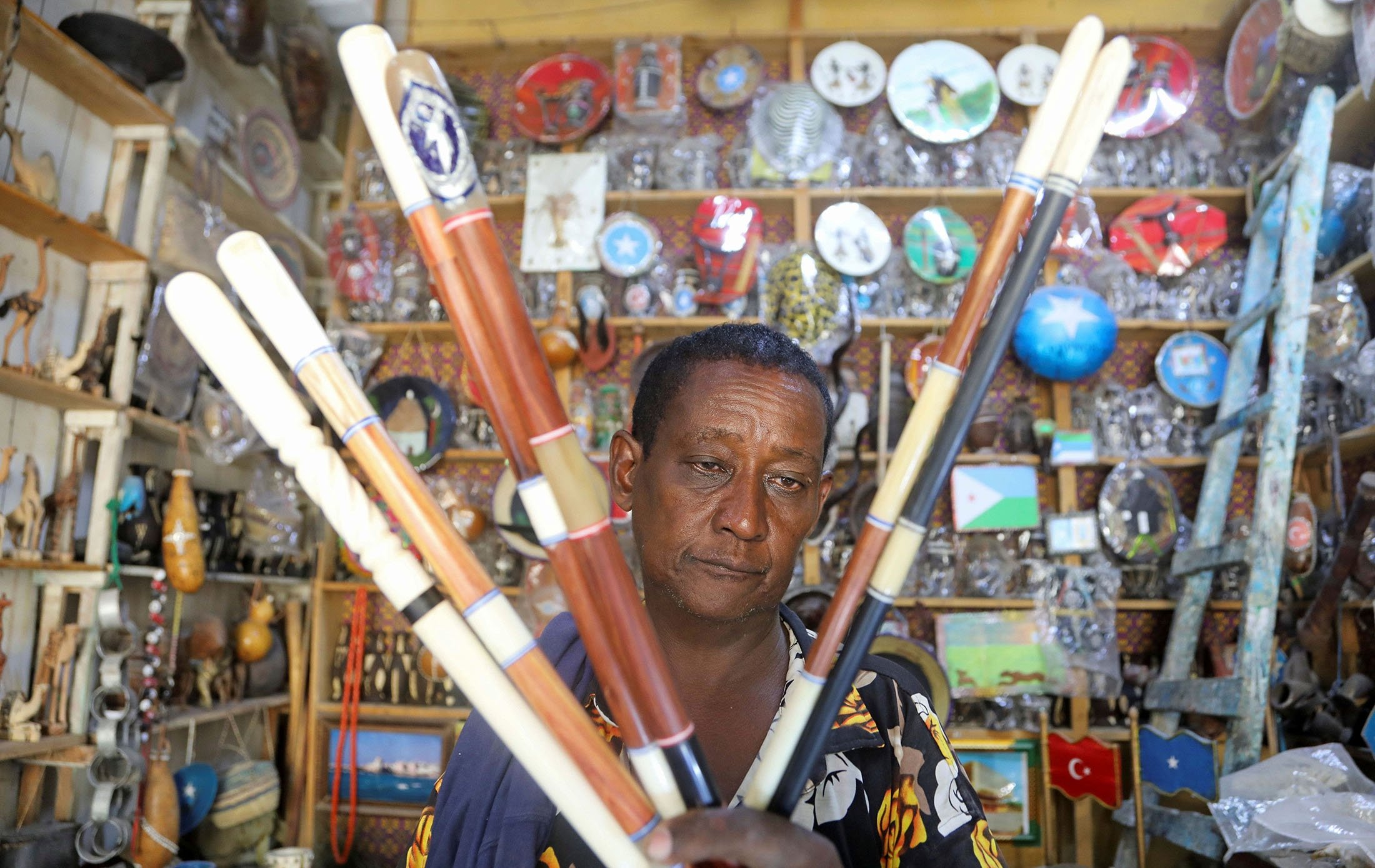 Perajin Somalia Muse Mohamud Olosow, 55, memegang tongkat polisi yang terbuat dari campuran kayu dan tulang unta, di tokonya di distrik Hamar Jajab di Mogadishu, Somalia, 23 Oktober 2021. (Foto Reuters)