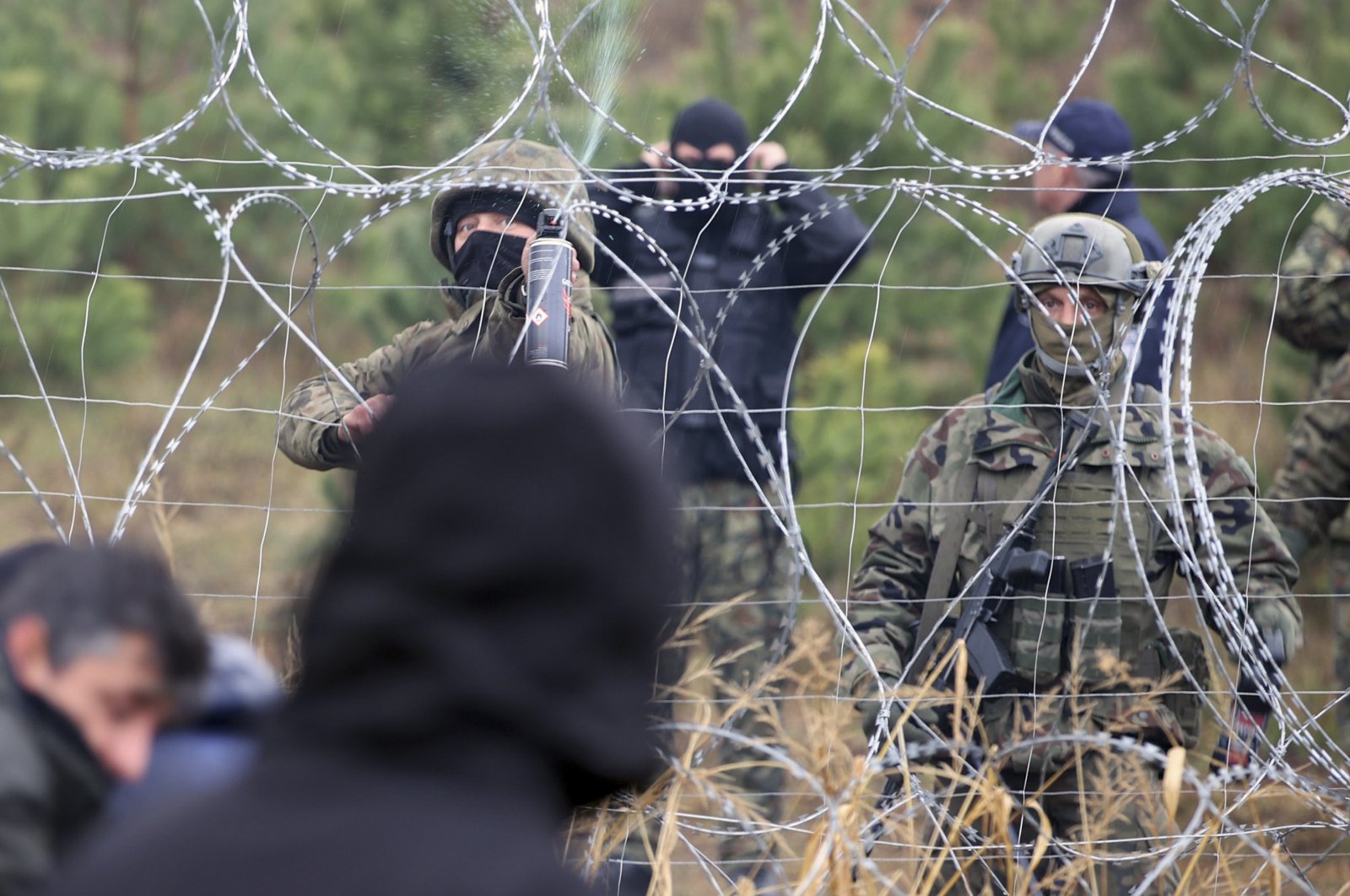Polish border guards stand near the barbed wire as migrants from the Middle East and elsewhere gather at the Belarus-Poland border near Grodno, Belarus, Monday, Nov. 8, 2021. (AP Photo)