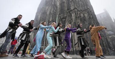 Young carnival revellers dance in front of the Cologne Cathedral when tens of thousands celebrate the start of the carnival season in the streets of Cologne, Germany, Nov. 11, 2021. (AP Photo)